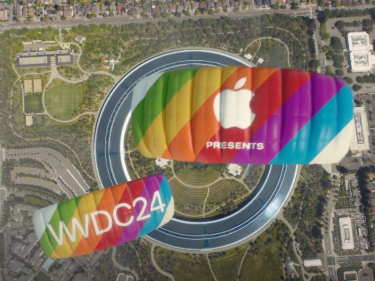 Se aprecia el Apple Park en el fondo y dos parapentes de color arcoiris, típico de Apple, en el que se puede ver en uno de ellos el logotipo de la marca y el texto Presenta, y en el otro parapente se puede leer la palabra WWDC 24 en letras de color blanco.