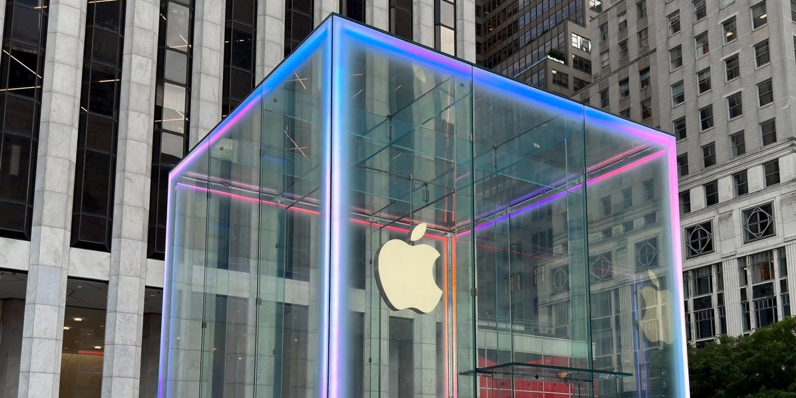 El cubo de cristal de la tienda de NYC iluminado con los colores de Apple Intelligence